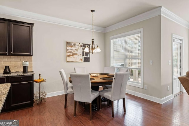 dining area with a chandelier, dark wood finished floors, and ornamental molding