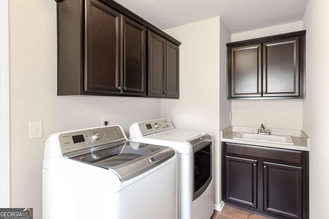 laundry area featuring light tile patterned floors, a sink, cabinet space, and washing machine and dryer