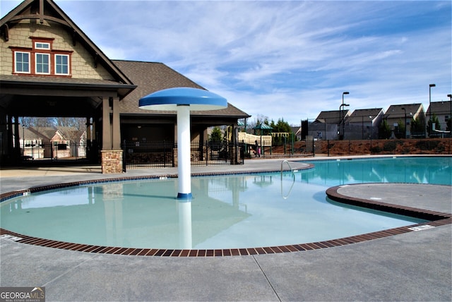community pool featuring a patio, playground community, and fence