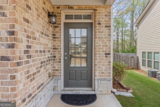 entrance to property with brick siding, fence, and stone siding