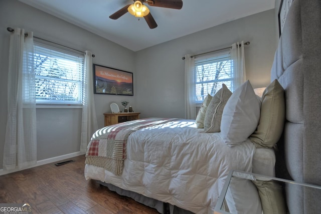 bedroom with baseboards, multiple windows, wood finished floors, and visible vents