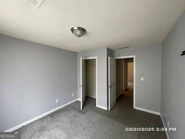 135 Flowers Dr, Covington, GA 30016 - unfurnished bedroom featuring visible vents, baseboards, a closet, dark colored carpet, and a textured ceiling