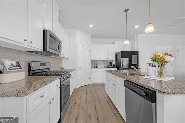 kitchen featuring light stone counters, white cabinetry, appliances with stainless steel finishes, and decorative backsplash