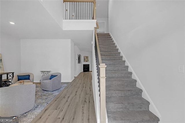 hallway featuring attic access, light wood-type flooring, visible vents, and an upstairs landing