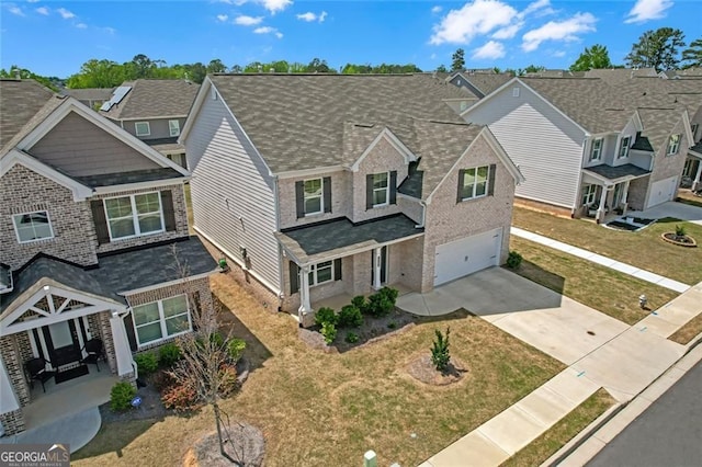 view of front of property featuring an attached garage, brick siding, driveway, and a front yard
