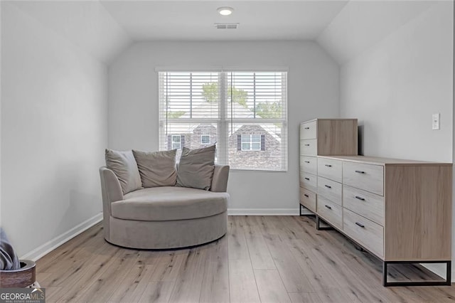 sitting room with lofted ceiling, baseboards, visible vents, and light wood finished floors