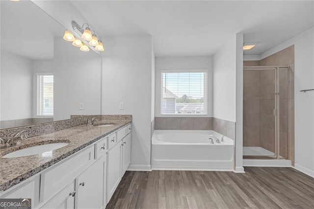 full bathroom with a shower stall, a garden tub, wood finished floors, and a sink