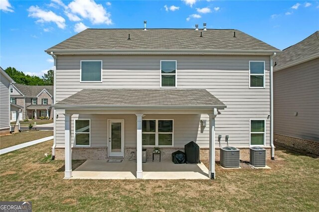 back of house featuring a patio area, brick siding, and a yard