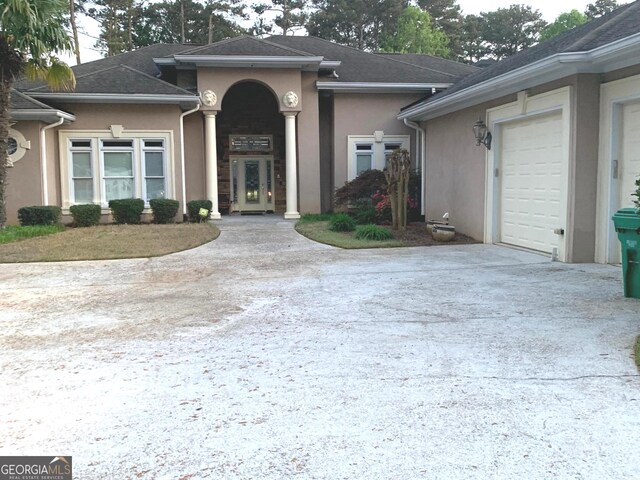 6279 Giles Rd, Lithonia, GA 30058 - view of exterior entry featuring stucco siding, concrete driveway, a garage, and french doors