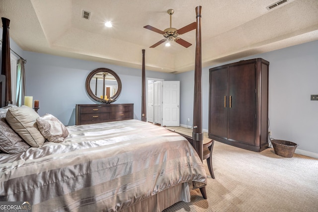 bedroom featuring visible vents, baseboards, a tray ceiling, and light colored carpet