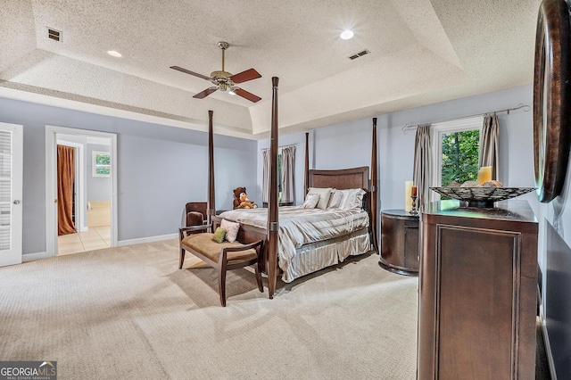 bedroom featuring a raised ceiling, visible vents, a textured ceiling, and light colored carpet