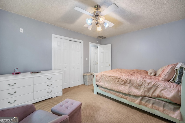 bedroom with a textured ceiling, light carpet, ceiling fan, and a closet