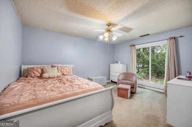 bedroom featuring carpet, a ceiling fan, a textured ceiling, and visible vents