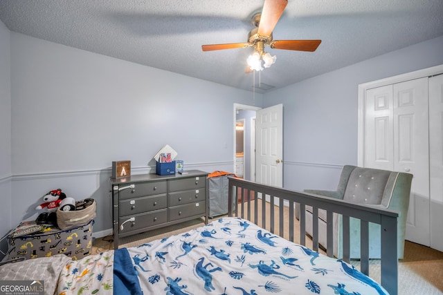 bedroom featuring a closet, a ceiling fan, carpet, and a textured ceiling