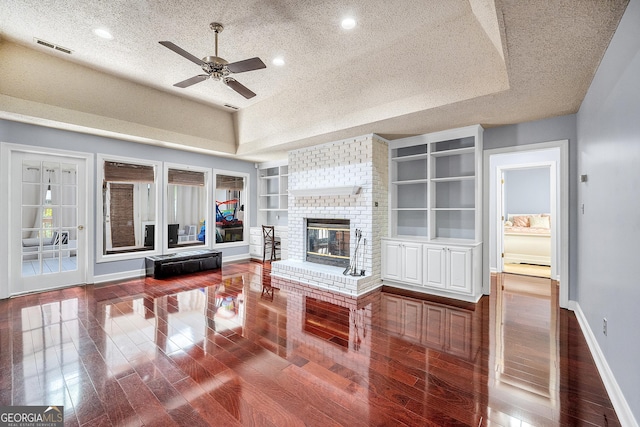 living area with ceiling fan, a textured ceiling, visible vents, wood finished floors, and baseboards
