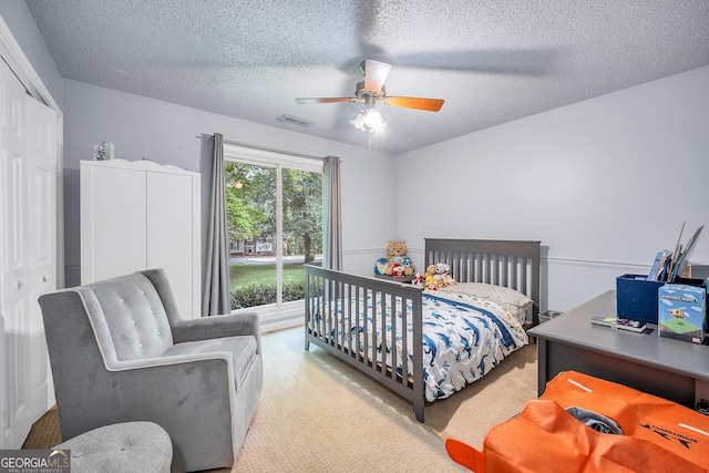 carpeted bedroom featuring a ceiling fan, a textured ceiling, visible vents, and a closet