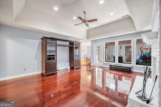 living room featuring a ceiling fan, a textured ceiling, visible vents, baseboards, and dark wood-type flooring