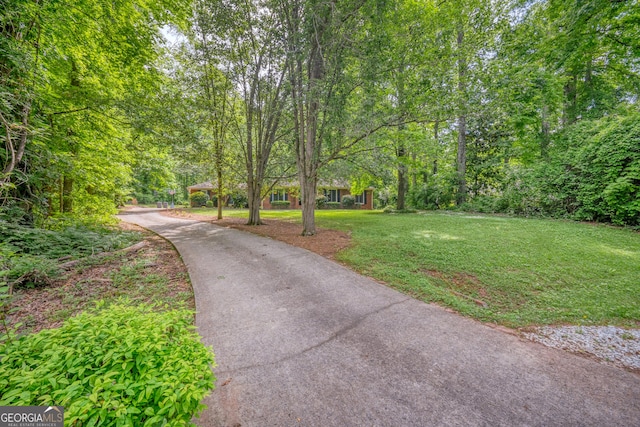 view of community with a lawn and aphalt driveway