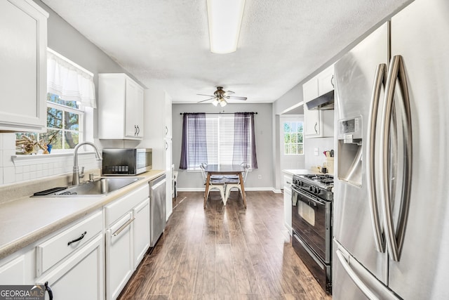 321 Harris Ave, Locust Grove, GA 30248 - kitchen featuring stainless steel appliances, a sink, dark wood-style floors, white cabinetry, and under cabinet range hood