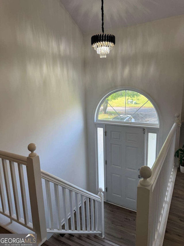 entrance foyer with a chandelier, wood finished floors, and a towering ceiling