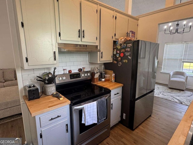 kitchen with tasteful backsplash, dark wood-style floors, under cabinet range hood, stainless steel appliances, and butcher block countertops