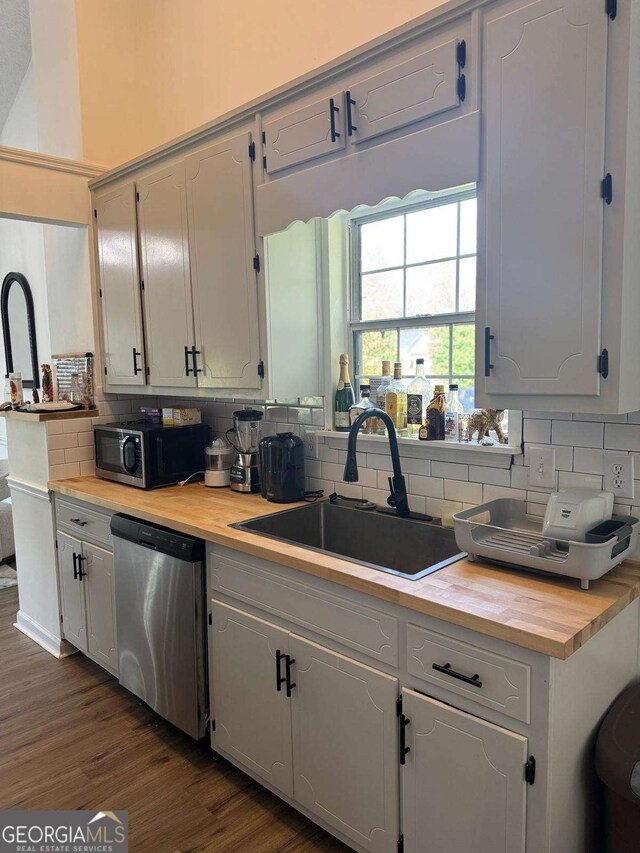 kitchen with stainless steel appliances, tasteful backsplash, butcher block countertops, and a sink