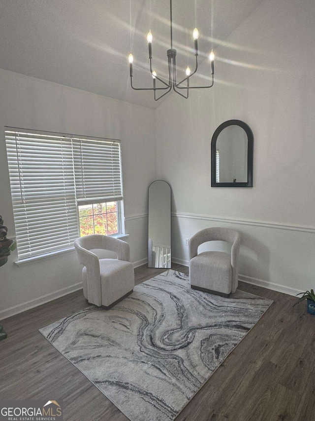 living area with a notable chandelier, baseboards, and wood finished floors