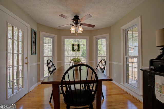 dining area featuring ceiling fan, light wood finished floors, and a textured ceiling