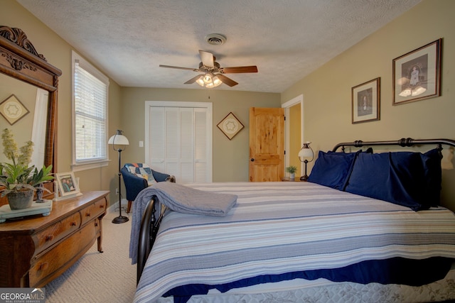 bedroom featuring a textured ceiling, a closet, carpet flooring, and ceiling fan