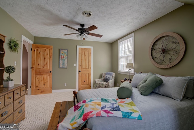 carpeted bedroom featuring visible vents, ceiling fan, baseboards, and a textured ceiling