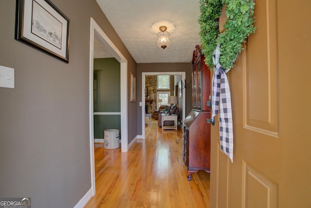foyer entrance featuring light wood-style floors, a textured ceiling, and baseboards
