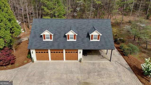 cape cod-style house with concrete driveway, a garage, and a shingled roof