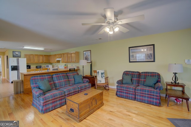 living room with light wood-style flooring, baseboards, and ceiling fan