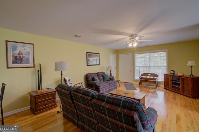 living room with light wood-style floors, visible vents, baseboards, and a ceiling fan