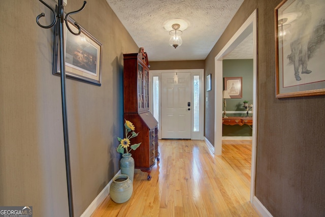 entrance foyer featuring a textured ceiling, baseboards, and wood finished floors