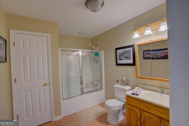 bathroom featuring toilet, vanity, tile patterned flooring, and bath / shower combo with glass door