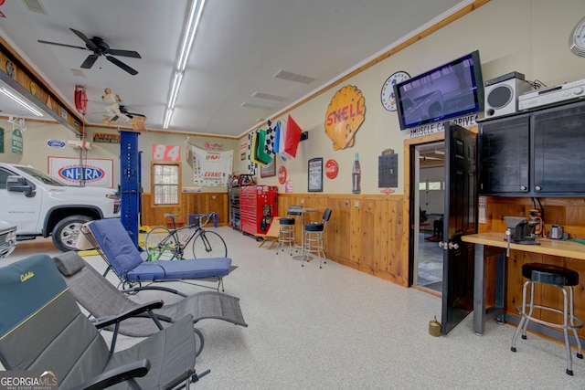 interior space featuring wooden walls, wainscoting, visible vents, and ceiling fan
