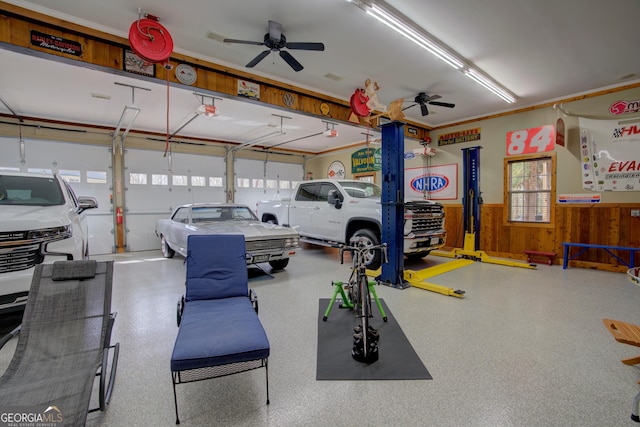 garage with a garage door opener, wood walls, ceiling fan, and a wainscoted wall