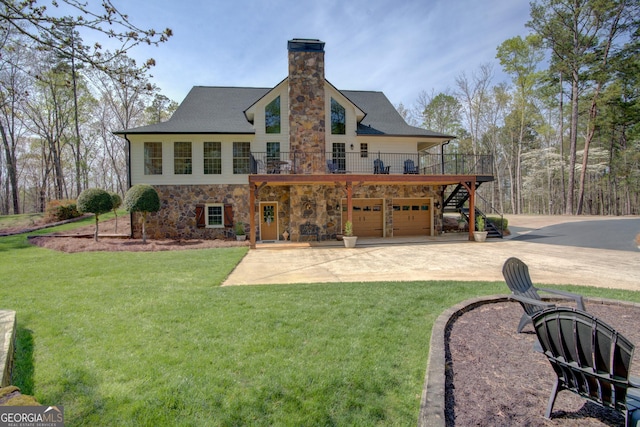 back of property featuring a yard, stone siding, an attached garage, a chimney, and driveway