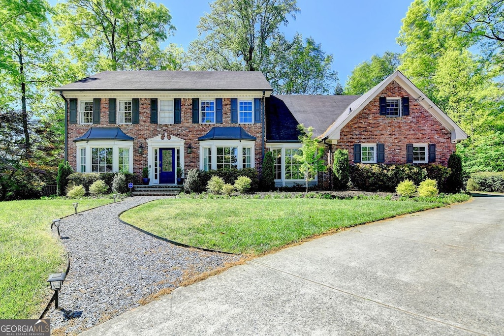 colonial-style house with brick siding and a front yard