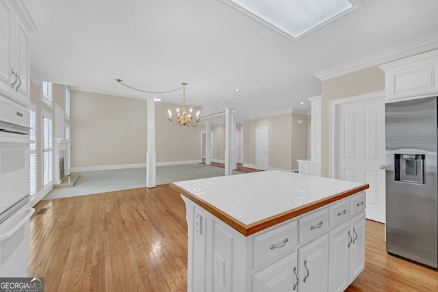 1405 Wilmington Way, Grayson, GA 30017 - kitchen with stainless steel fridge, ornamental molding, white cabinetry, light wood finished floors, and a chandelier