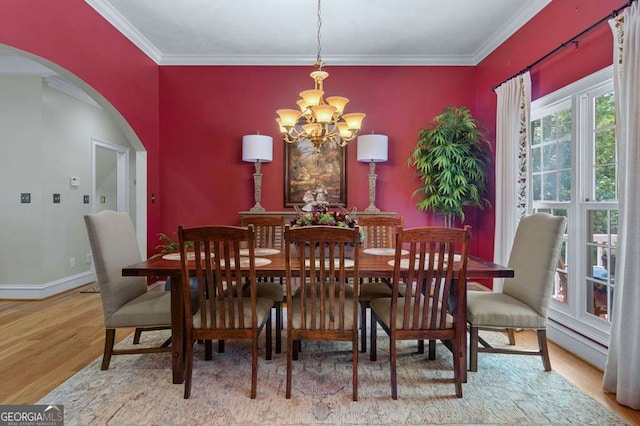 dining space with baseboards, arched walkways, an inviting chandelier, ornamental molding, and wood finished floors