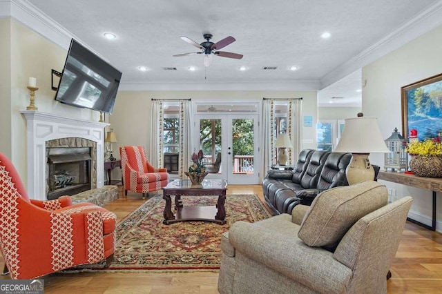 living room with ornamental molding, a ceiling fan, wood finished floors, and a healthy amount of sunlight