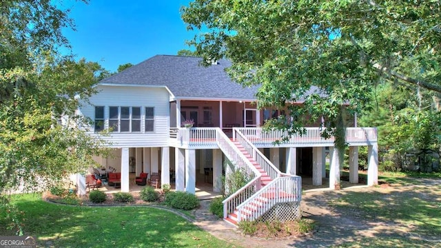 back of house featuring a sunroom, a patio area, a lawn, stairway, and roof with shingles