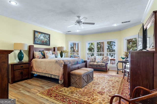 bedroom with visible vents, ornamental molding, wood finished floors, and a textured ceiling