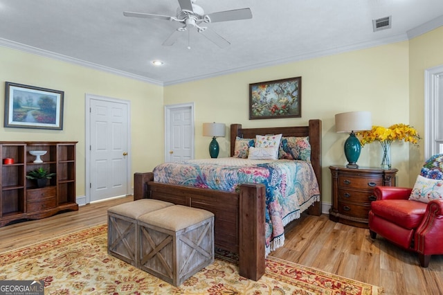 bedroom with crown molding, visible vents, baseboards, and wood finished floors