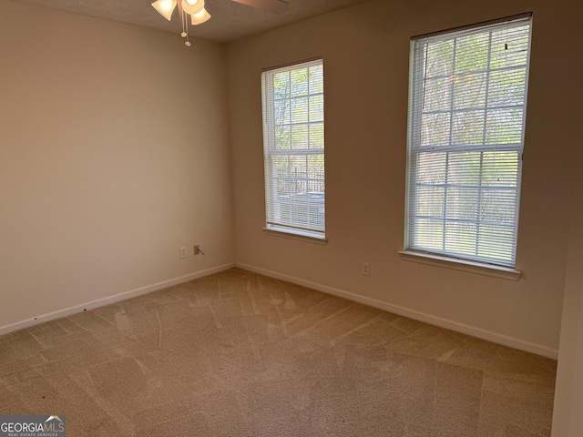 unfurnished room featuring light colored carpet, ceiling fan, and baseboards