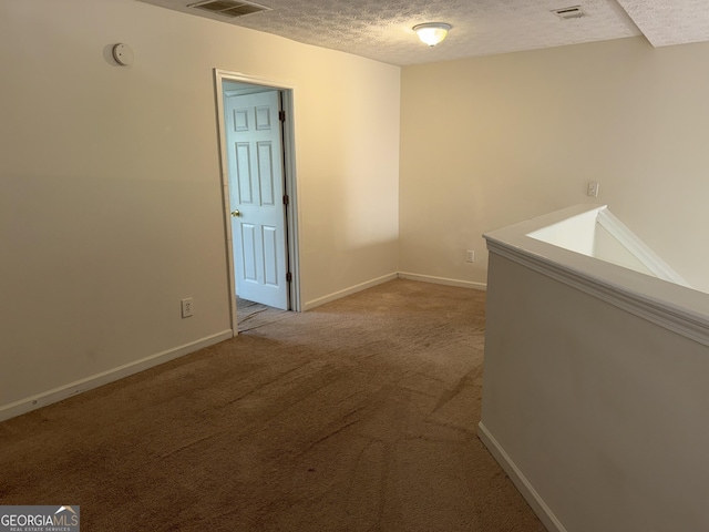 interior space with visible vents, baseboards, light colored carpet, and a textured ceiling
