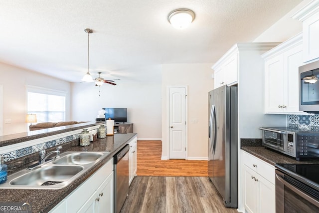kitchen featuring dark countertops, a sink, white cabinetry, and stainless steel appliances