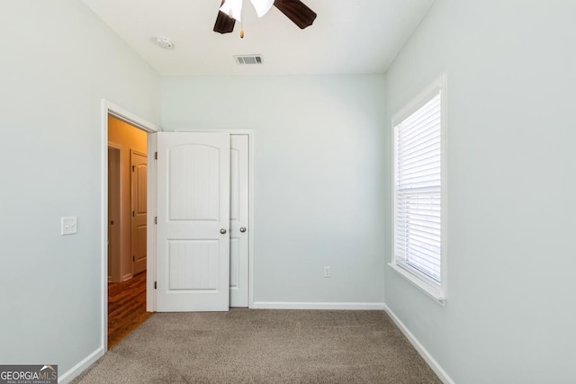 unfurnished bedroom featuring carpet, baseboards, multiple windows, and visible vents